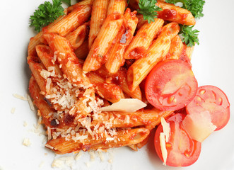 Plate with delicious penne pasta and garnish, closeup