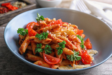 Plate with delicious penne pasta and garnish on table, closeup