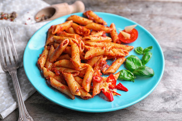 Plate with delicious penne pasta and garnish on table