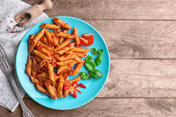 Plate with delicious penne pasta and garnish on table