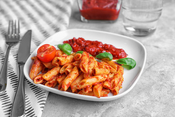 Plate with delicious penne pasta and garnish on table
