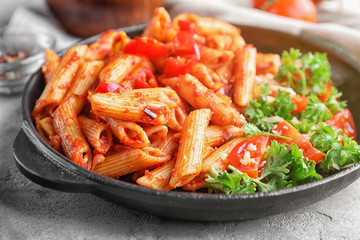 Plate with delicious penne pasta and garnish on table, closeup