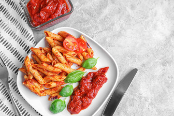 Plate with delicious penne pasta and garnish on table