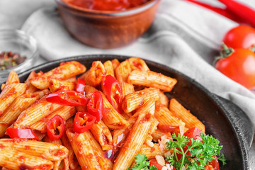 Plate with delicious penne pasta and garnish on table, closeup