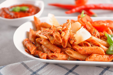 Plate with delicious penne pasta and garnish on table, closeup