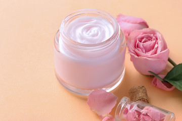 Fototapeta na wymiar Jar of body cream and flowers on color background
