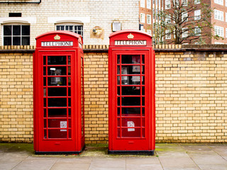 Two Bright Red Traditional British Telephone Boxes in Front of a Brick Wall