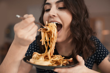 Young woman eating tasty pasta in cafe - Powered by Adobe