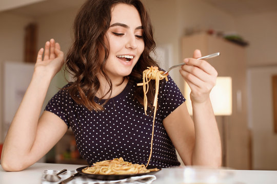 Young Woman Eating Tasty Pasta At Table