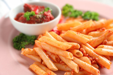 Tasty penne pasta with tomato sauce on plate, closeup