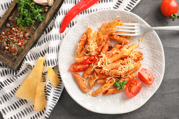 Plate of tasty penne pasta with tomato sauce on grey table