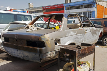 A wrecked car to be painted in a repair shop in the street