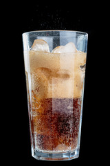 fizzy drink with ice in glass on dark background