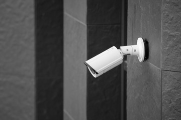 Modern CCTV camera on wall of building outdoors