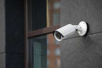 Modern CCTV camera on wall of building outdoors