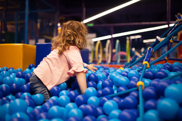 Happy little girl child in colourful blue plastic balls pool.