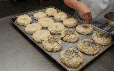 baker making bagel, adding seeds