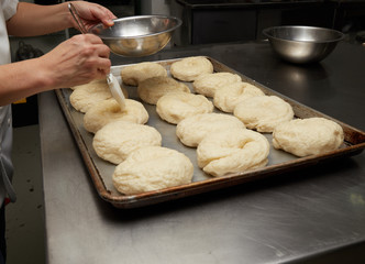 baker making bagel, adding beaten egg