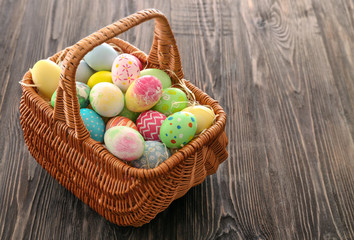 Easter basket with colorful eggs on wooden background