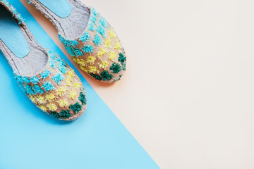 Fototapeta premium Summer fashion flatlay with gradient espadrille sandals on the two-toned blue and beige background. Perfect beach set for holidays on the sea. Marina style.