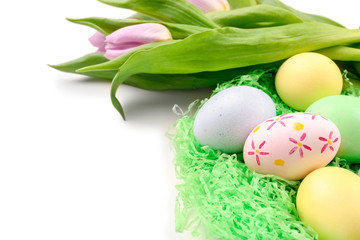 Obraz na płótnie Canvas Decorative nest with dyed Easter eggs and spring flowers on white background