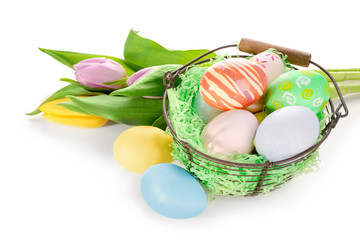 Easter basket with colorful eggs and bouquet of flowers on white background