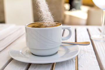 white cappuccino cup on a white wooden table drop sugar