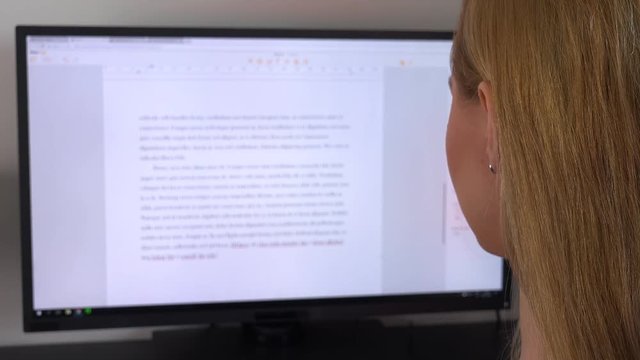 A blonde woman reads a text on a computer screen - closeup