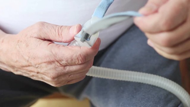 A senior man looks over the headgear part of his CPAP machine
