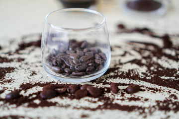 Coffee beans in a cup with coffee powder spread on the side