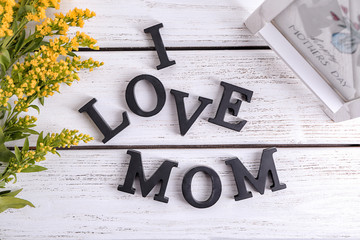 Phrase "I love mom" made of letters on wooden background. Greeting for Mother's day