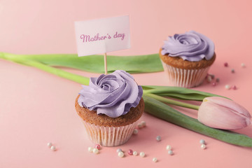 Tasty cupcakes, tulip and topper pick with words MOTHER'S DAY on color background