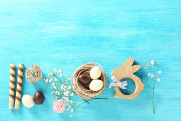 Fototapeta na wymiar Beautiful composition with chocolate Easter eggs and decorative bunny on color wooden background