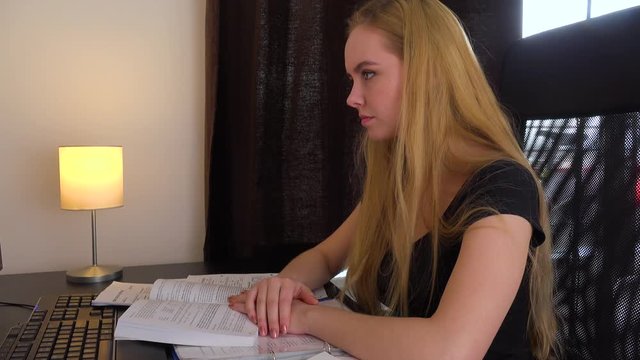A young beautiful woman sits at a desk in front of a computer and acts frustrated - closeup