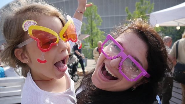 Weekend family amuse nanny with child girl on hands in funny glasses show tongue grimace posing on camera