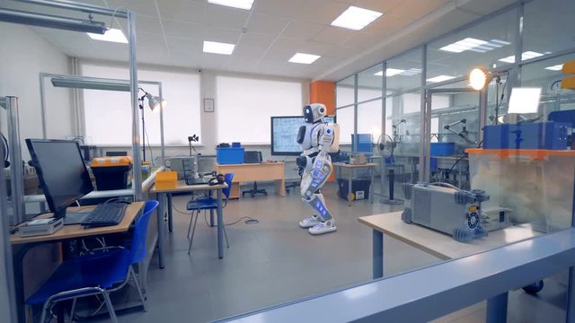 A white robot stands in a room.