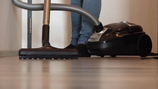 A woman vacuums a hall in an apartment - closeup from the floor