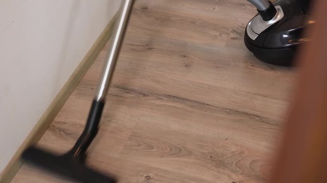 A woman vacuums a hall in an apartment - closeup