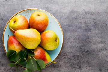 Fresh bio pear with leaves on the plate. Gray stone table.