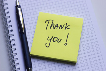 Yellow sticky note on white notepad with the words Thank You