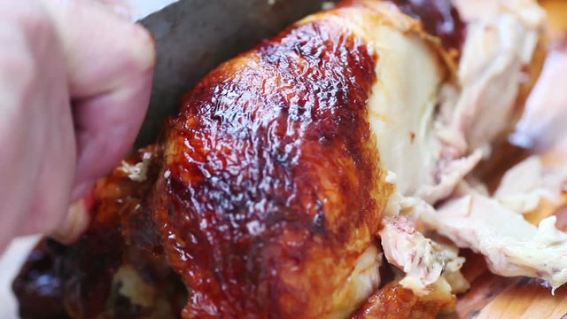 A man finds it very difficult to cut up a rotisserie chicken