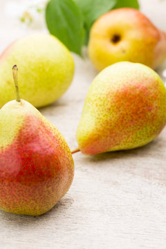Fresh pears with leaves in a on wooden background.
