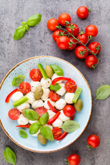 Delicious caprese salad with ripe cherry tomatoes and mini mozzarella cheese balls with fresh basil leaves.