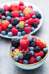 Fresh berry salad on blue dishes. Vintage wooden background.