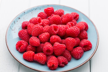 Fresh raspberries in a plate on a  vintage background.