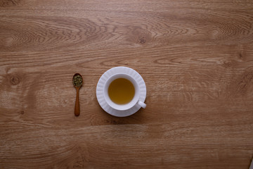 A cup of hot tea put on natural brown wood texture table with a wood spoon.