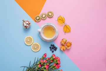 A glass of hot tea with dried fruits and glasses, flower decorated on mix color crop background.