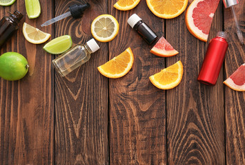 Bottles of essential oil and citrus slices on wooden table