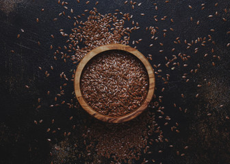 Raw flax seeds in bowl, stone background, top view