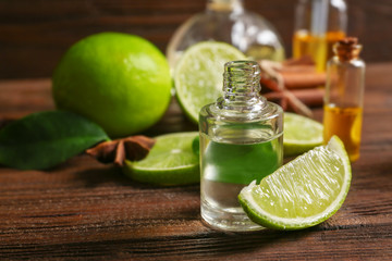 Bottle with citrus essential oil and slice of lime on wooden table